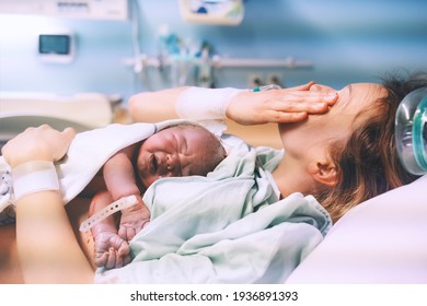 Mother and newborn. Child birth in maternity hospital. Young mom hugging her newborn baby after delivery. Woman giving birth. First moments of baby life after labor. - Shutterstock ID 1936891393