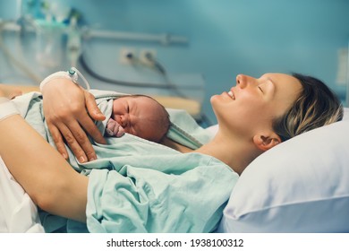 Mother and newborn. Child birth in maternity hospital. Young mom hugging her newborn baby after delivery. Woman giving birth. First moments of baby life after labor. - Shutterstock ID 1938100312