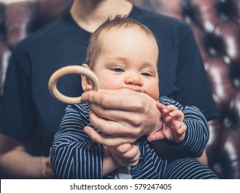 A Mother Is Offering Her Baby A Teething Ring To Chew On