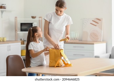 Mother Packing School Lunch For Her Little Daughter At Home