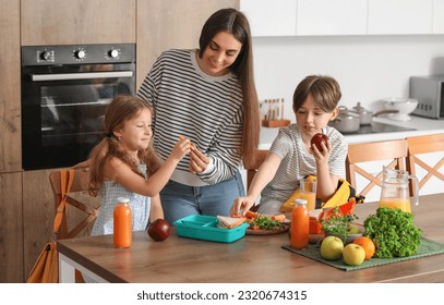 Mother packing school lunch for her little children in kitchen - Powered by Shutterstock