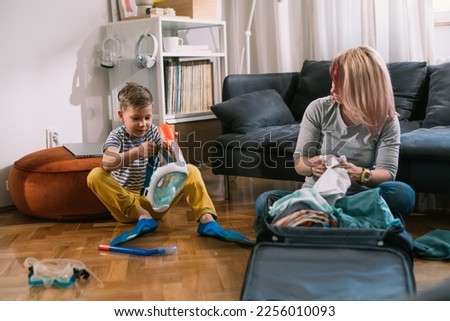 Mother is packing a suitcase for a trip with her son
