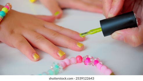 Mother Painting Daughter's Nails with Neon Green Polish, Close-Up with Colorful Bracelet. High quality photo - Powered by Shutterstock