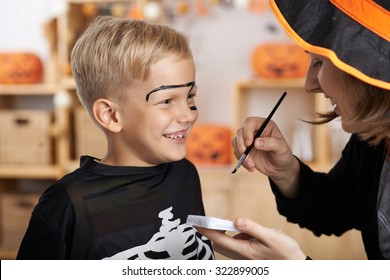 Mother Painting Face Of Her Son For Halloween Celebration