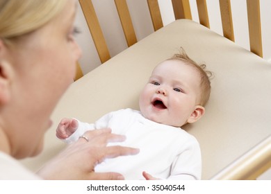 Mother Playing With Baby In Cot