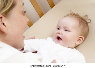 Mother Playing With Baby In Cot