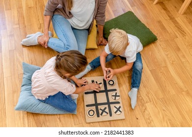 Mother playing with children a Tic-Tac-Toe game. Educational games for kids. Mother-children creative time together.