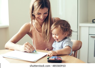 Mother playing and her 1 4 years old son  drawing together