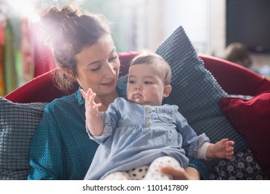 Mother is playing with her cheerful baby on the couch at home - Shutterstock ID 1101417809