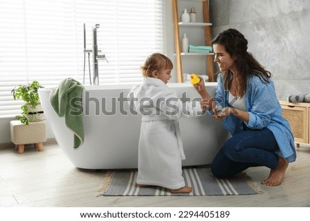 Mother playing with her daughter near tub in bathroom