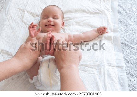 Mother playing with her infant baby holding her feet. Concept of pure and unbreakable love
