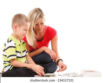 mother playing puzzle together with her son on floor isolated on white background