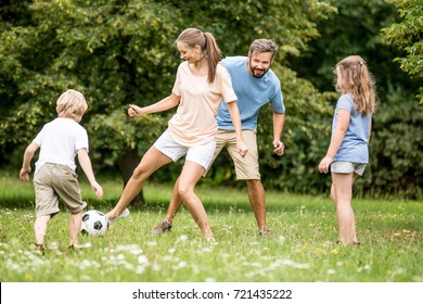 Mother plays football soccer with family in summer  - Shutterstock ID 721435222