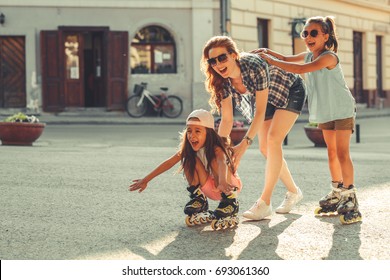 Mother plays with her daughters on street in neighborhood.They drive roller blades .Family concept.