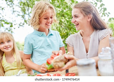 Mother prepares a baguette with tomatoes for her son for breakfast