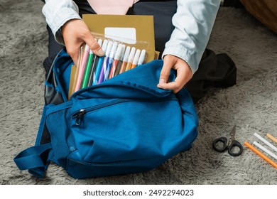 A mother prepares and packs her child's school supplies into their school bag - Powered by Shutterstock