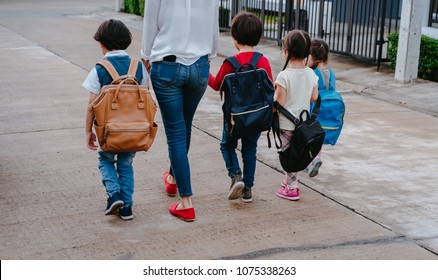 Mother And Pupil And Kids Holding Hands Going To School In First Class With Schoolbag Or Satchel Walking To School Bus, Parent And Son,sister Preschool 