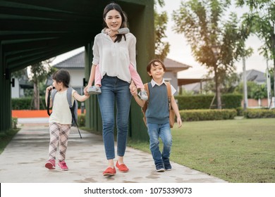 Mother And Pupil And Kids Holding Hands Going To School In First Class With Schoolbag Or Satchel Walking To School Bus, Parent And Son,sister Preschool 