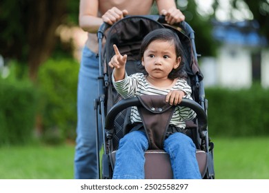 mother pushing toddler baby stroller and walking in the park - Powered by Shutterstock