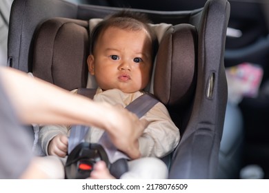 Mother Put Cute Baby To Car Seat And Secure With Safety Belts. Asian Infant Baby Sit In Baby Seat And Looking Around In Car.mom Buckling Her Son To Car Seat.Baby Safety On Car Concept