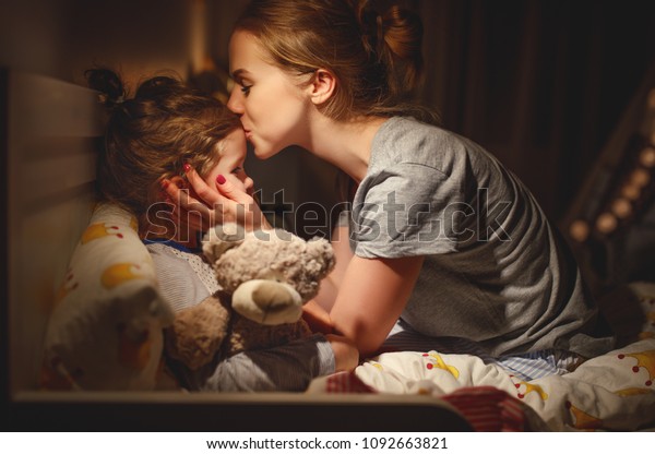  mother puts her daughter to bed and kisses her\
in the evening\
