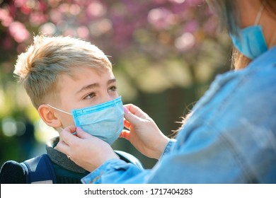 Mother Puts Her Son A Face Protective Mask Outdoors. Coronavirus, Illness, Infection, Quarantine, Medical Mask, COVID-19. Coronavirus Quarantine. Closeup Medical Mask. Kid Wearing Face Mask.