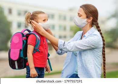 A Mother Puts A Protective Face Mask On Her Daughter A Student With A Backpack On Her Back On The Street Near The School