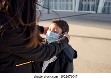 Mother Puts A Safety Mask On Her Child's Face. Child Going To Play In The Park With Covid-19 Precautions. Medical Mask To Prevent Coronavirus. Coronavirus Quarantine, New Normal.