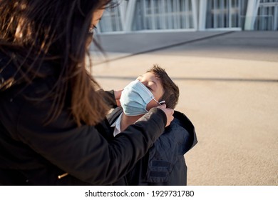 Mother Puts A Safety Mask On Her Child's Face. Child Going To Play In The Park With Covid-19 Precautions. Medical Mask To Prevent Coronavirus. Coronavirus Quarantine, New Normal.