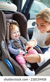 Mother Putting Baby Into Car Seat