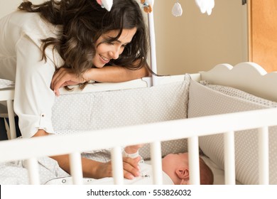 Mother Putting Baby To Sleep At The Crib