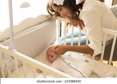 Mother Putting Baby To Sleep At The Crib