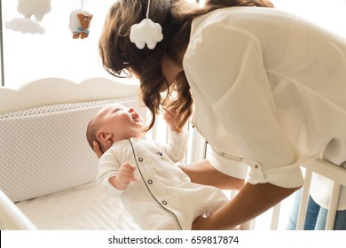 Mother Putting Baby To Sleep At The Crib