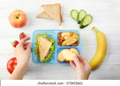Mother Putting Food In Lunch Box, Top View