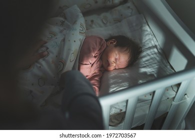 Mother putting her newborn baby two months old to sleep in the cradle bed at night in dark room - maternity and parenthood care concept - Powered by Shutterstock