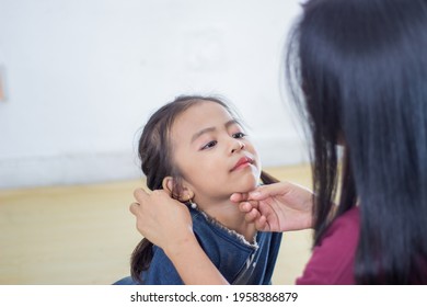 Mother Putting Lipstick On Her Daughter On Blurry Background. Mom Dresses Up And Makes Make-up Her Daughter. Selective Focus.