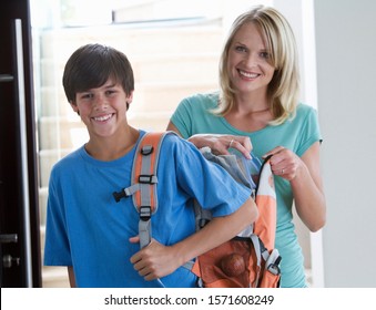 A Mother Putting A Packed Lunch In Her Son's Rucksack