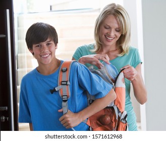 A Mother Putting A Packed Lunch In Her Son's Rucksack