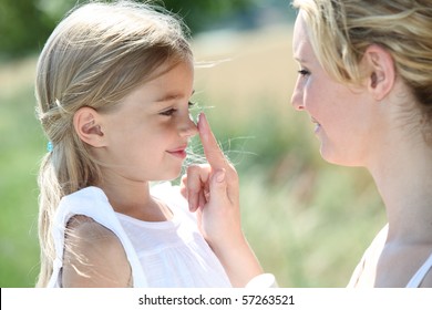 Mother Putting Sunscreen On Her Daughter's Nose