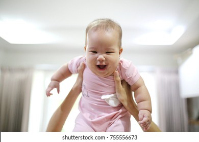 Mother Reach Hand Lift Up Play And Show Throws Cute Happy Baby On Sky In House Living Room At Morning Time After Awake Concept. Enjoy Parenting Emotion And Good Feeling Family.