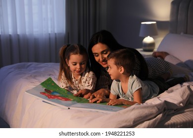 Mother Reading Bedtime Story To Her Children At Home