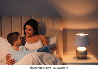 Mother Reading Bedtime Story To Her Son At Home