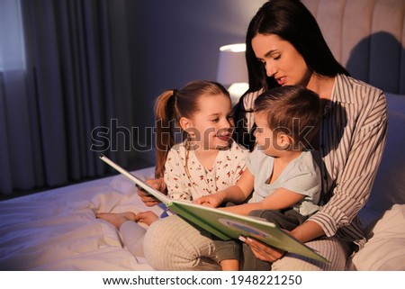 Mother reading bedtime story to her children at home