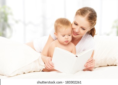 Mother Reading A Book The Baby In Bed Before Going To Sleep