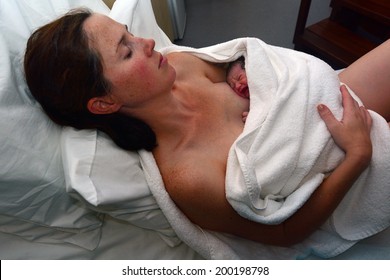 Mother rest with her newborn baby relieve in bed immediately after a natural water birth labor. Concept photo of  pregnant woman, newborn, baby, pregnancy. Real people. Copy space - Powered by Shutterstock