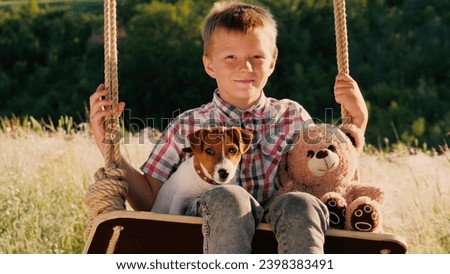 Mother rocks son and plush toy on swing while Jack Russell Terrier sits watching over. Mother sways son with Jack Russell Terrier sitting close. Mother with Jack Russell Terrier remains nearby