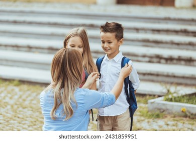 Mother saying goodbye to her little children near school. Mother taking kids to school. Beginning of lessons. First day of fall. - Powered by Shutterstock