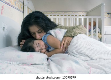 Mother Saying Goodnight And Tucking Her Daughter Into Bed