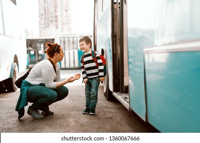 Mother Saying Talking With Her Son While Crouching In Front Of Bus. Kid Going To School.