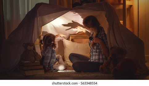 mother scares child daughter tells scary stories, plays in the theater of shadows - Shutterstock ID 563348554